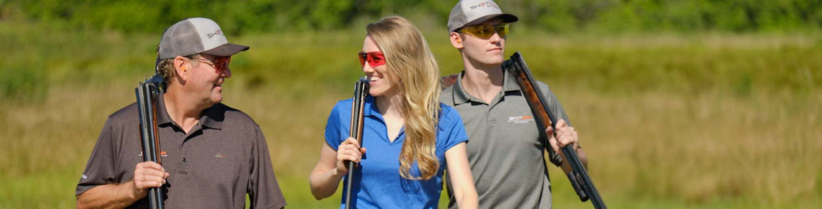 and Zander Stewart walk together in an outdoor shooting each carrying They wear ShotKam caps and protective shooting