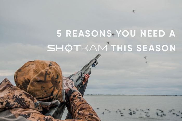 Outdoor hunter in camouflage aiming a shotgun equipped with a ShotKam camera system.