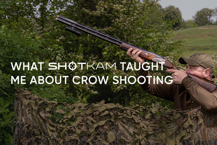 Hunter aiming at incoming crows from a camouflage hide with a ShotKam mounted beneath the shotgun barrel