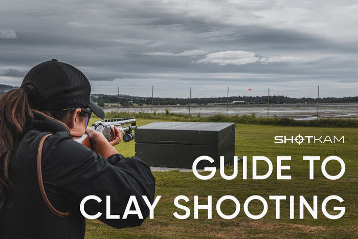 Woman aiming a shotgun with a ShotKam at an orange clay target