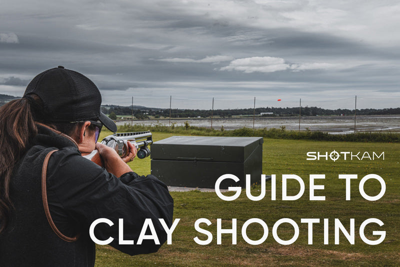 Woman aiming a shotgun with a ShotKam at an orange clay target
