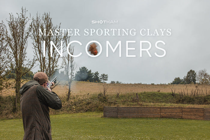 Shooter breaking an incoming clay target in the field, captured mid-shot with smoke from the barrel—Master Sporting Clays series by ShotKam.