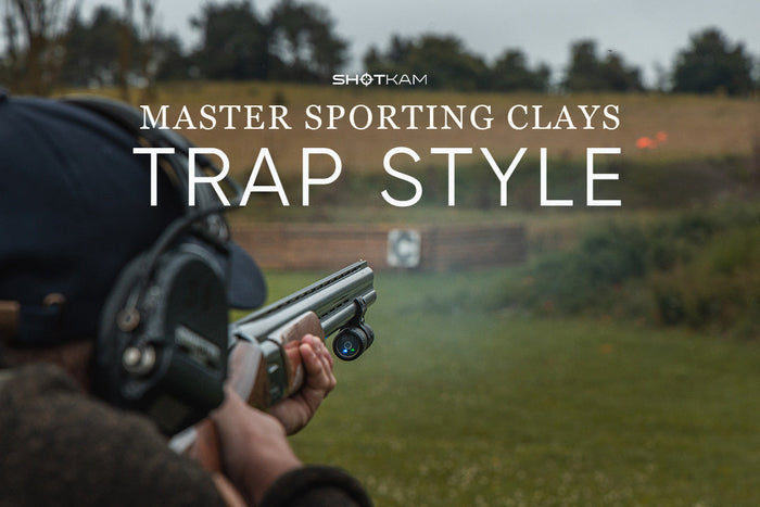 Shooter aiming at trap-style clay target with ShotKam mounted on barrel during sporting clays session in the USA.