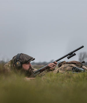 Hunter in camouflage gear with a rifle in a grassy field bird hunting with ShotKam