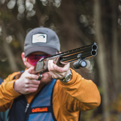 A sporting clays shooter aims with a ShotKam Gen 4 Mini attached to his shotgun. The lightweight camera records every shot for analysis and skill improvement.